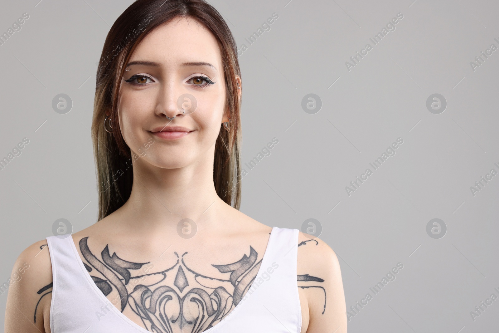 Photo of Portrait of beautiful tattooed woman on grey background. Space for text