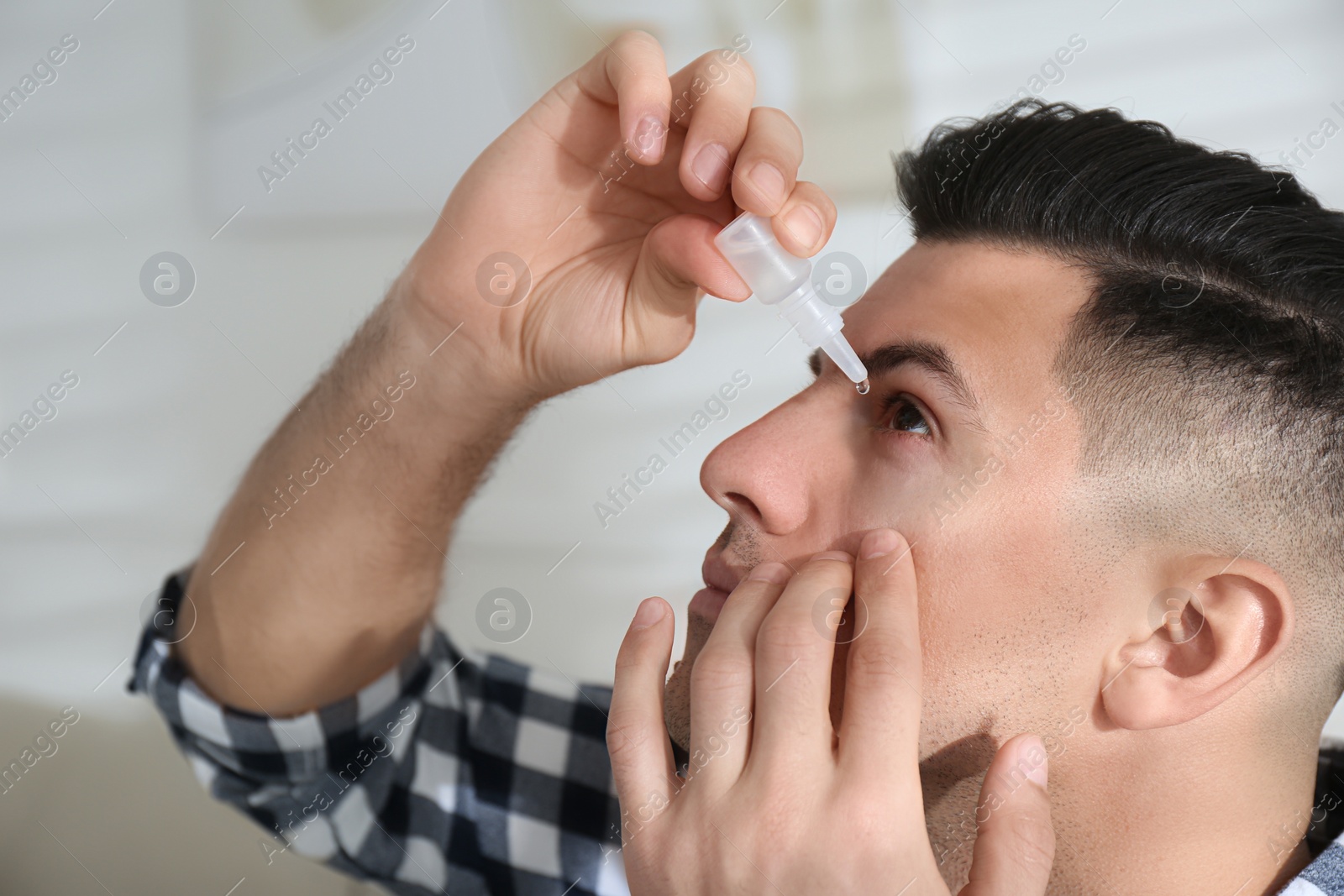 Photo of Man using eye drops in living room