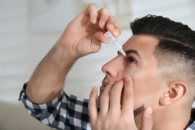 Photo of Man using eye drops in living room