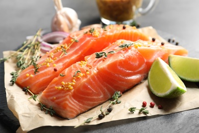 Photo of Fresh salmon and ingredients for marinade on slate plate, closeup
