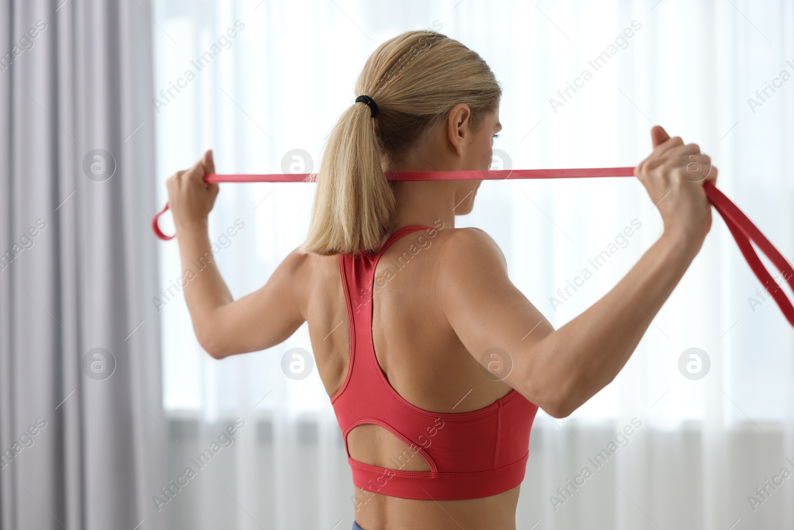 Photo of Fit woman doing exercise with fitness elastic band indoors