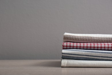 Stack of soft kitchen towels on wooden table against grey background, space for text