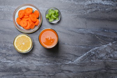 Photo of Tasty carrot juice and ingredients on black marble table, flat lay. Space for text