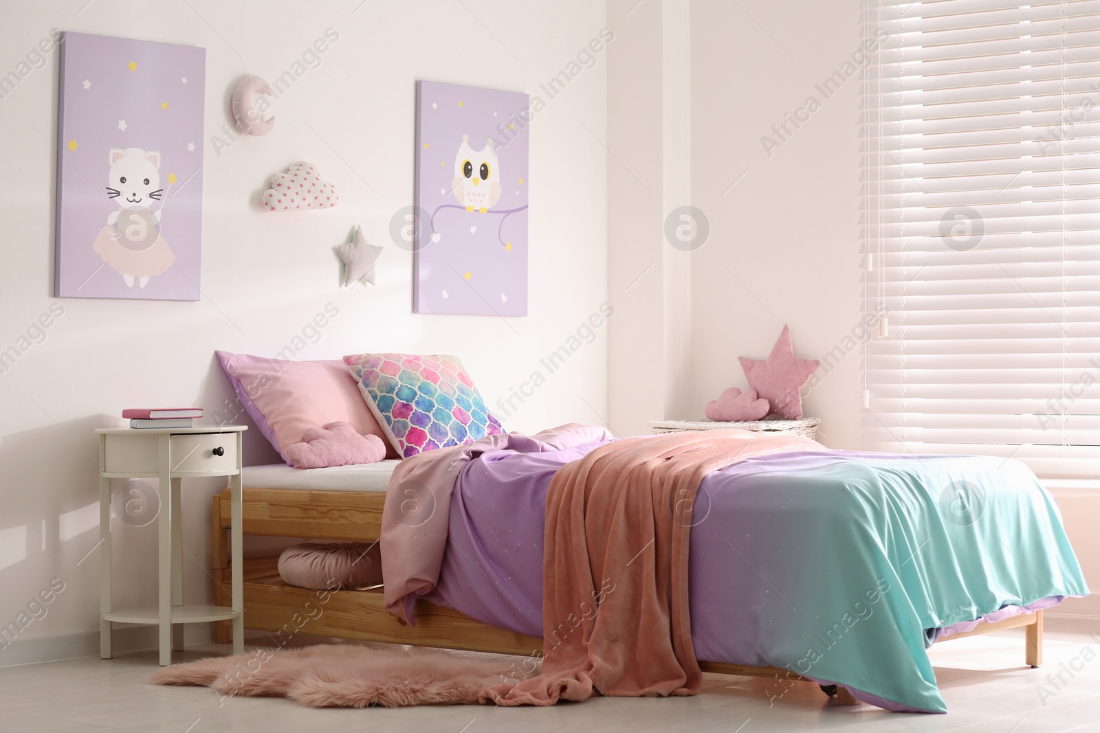 Photo of Bed with colorful linen in stylish children's room. Interior design