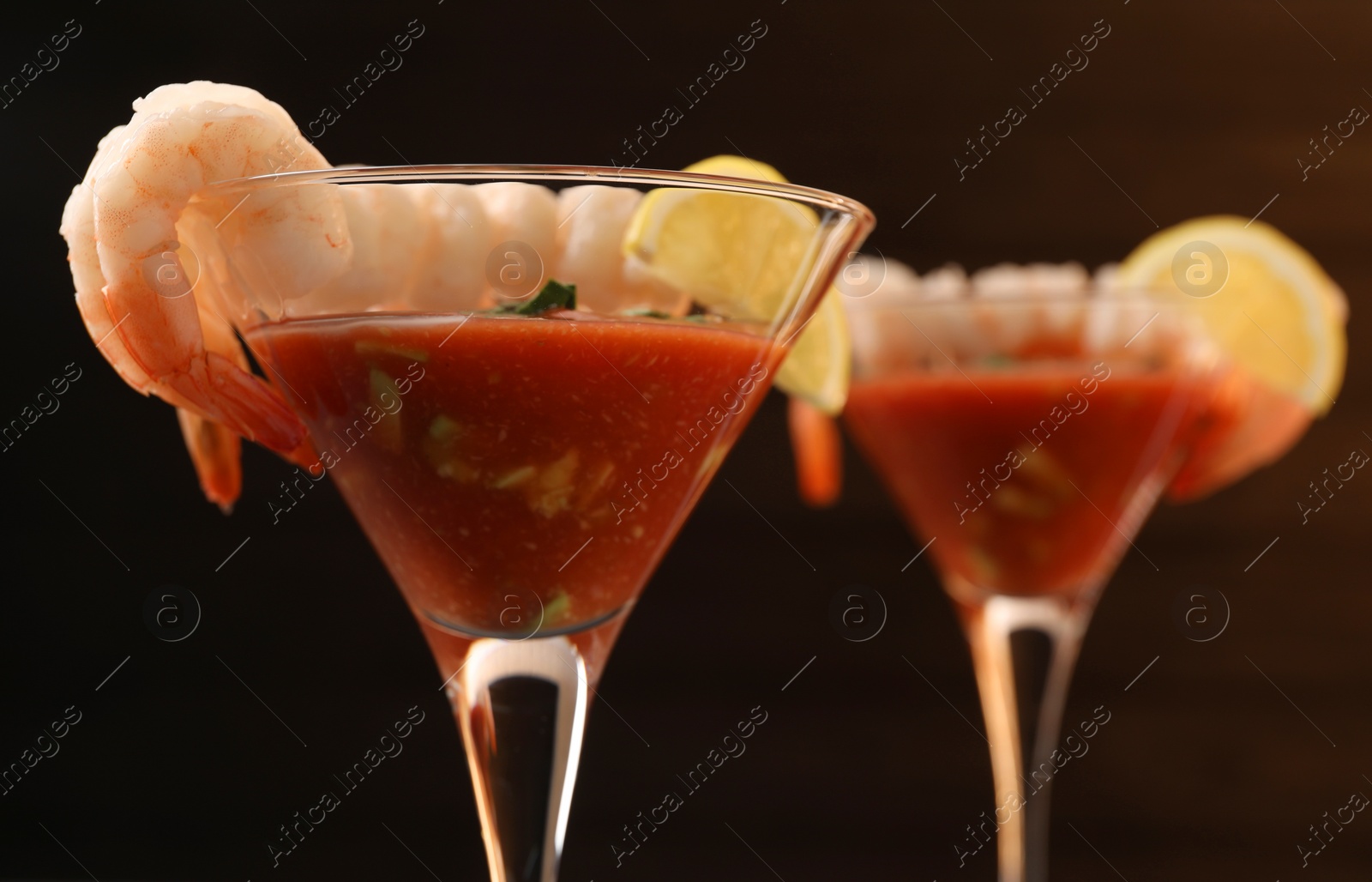 Photo of Tasty shrimp cocktail with sauce in glasses on dark background, closeup
