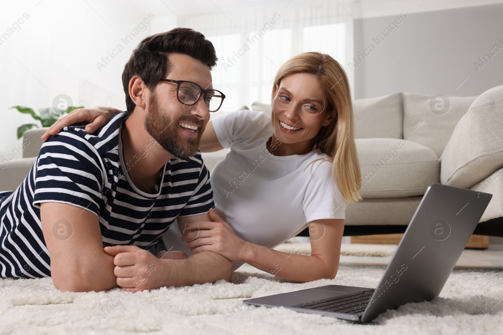 Photo of Happy couple with laptop on floor at home