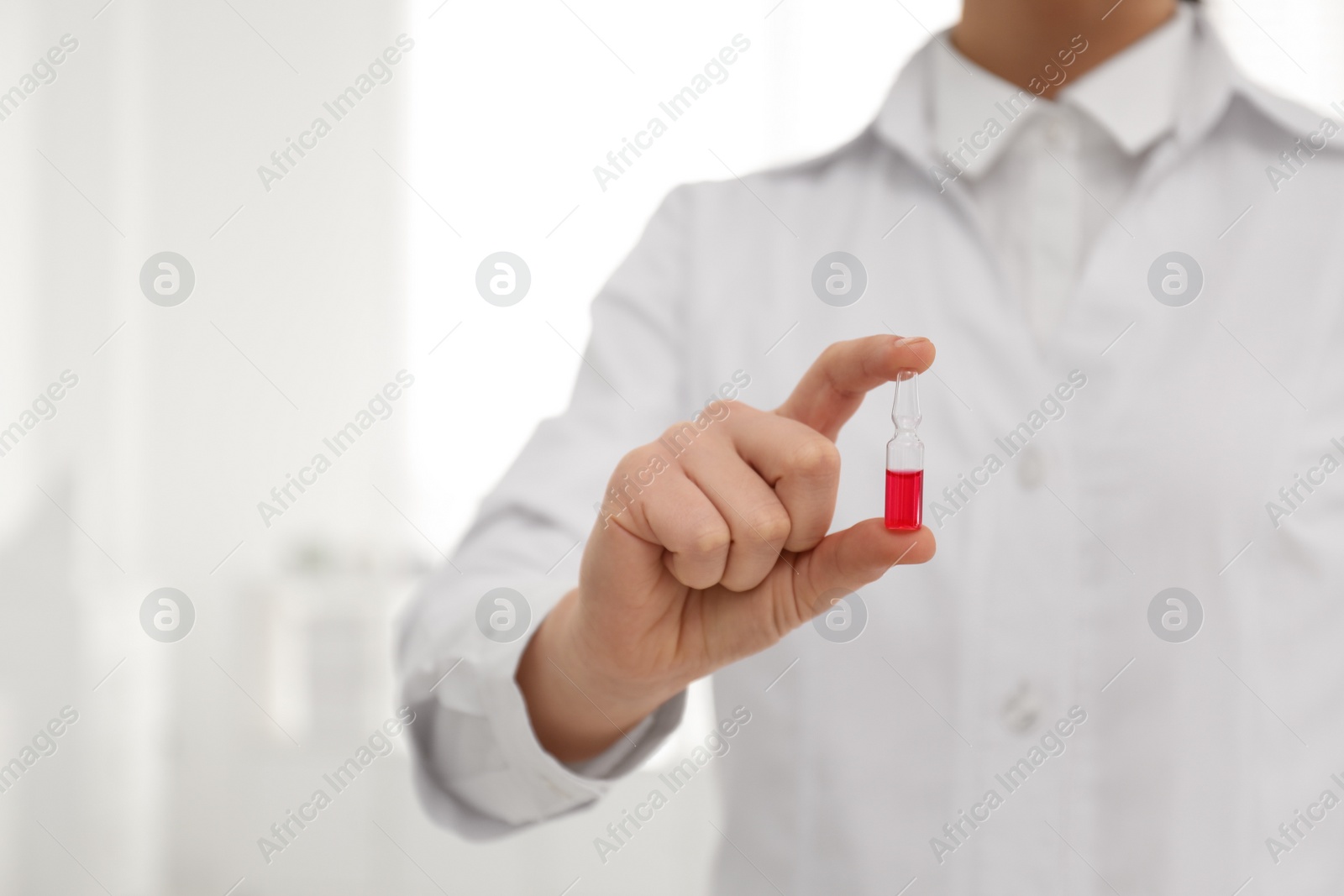 Photo of Professional pharmacist with ampule of medicine in drugstore, closeup