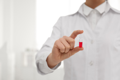 Photo of Professional pharmacist with ampule of medicine in drugstore, closeup