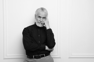 Image of Portrait of handsome senior man against light wall, space for text. Black and white effect