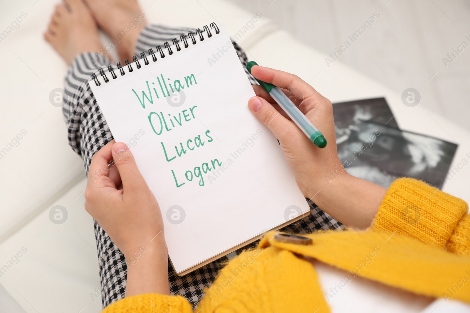 Photo of Pregnant woman with baby names list sitting on sofa, closeup