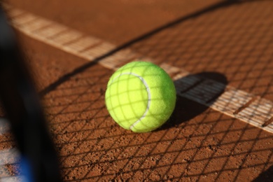 Bright yellow tennis ball on clay court