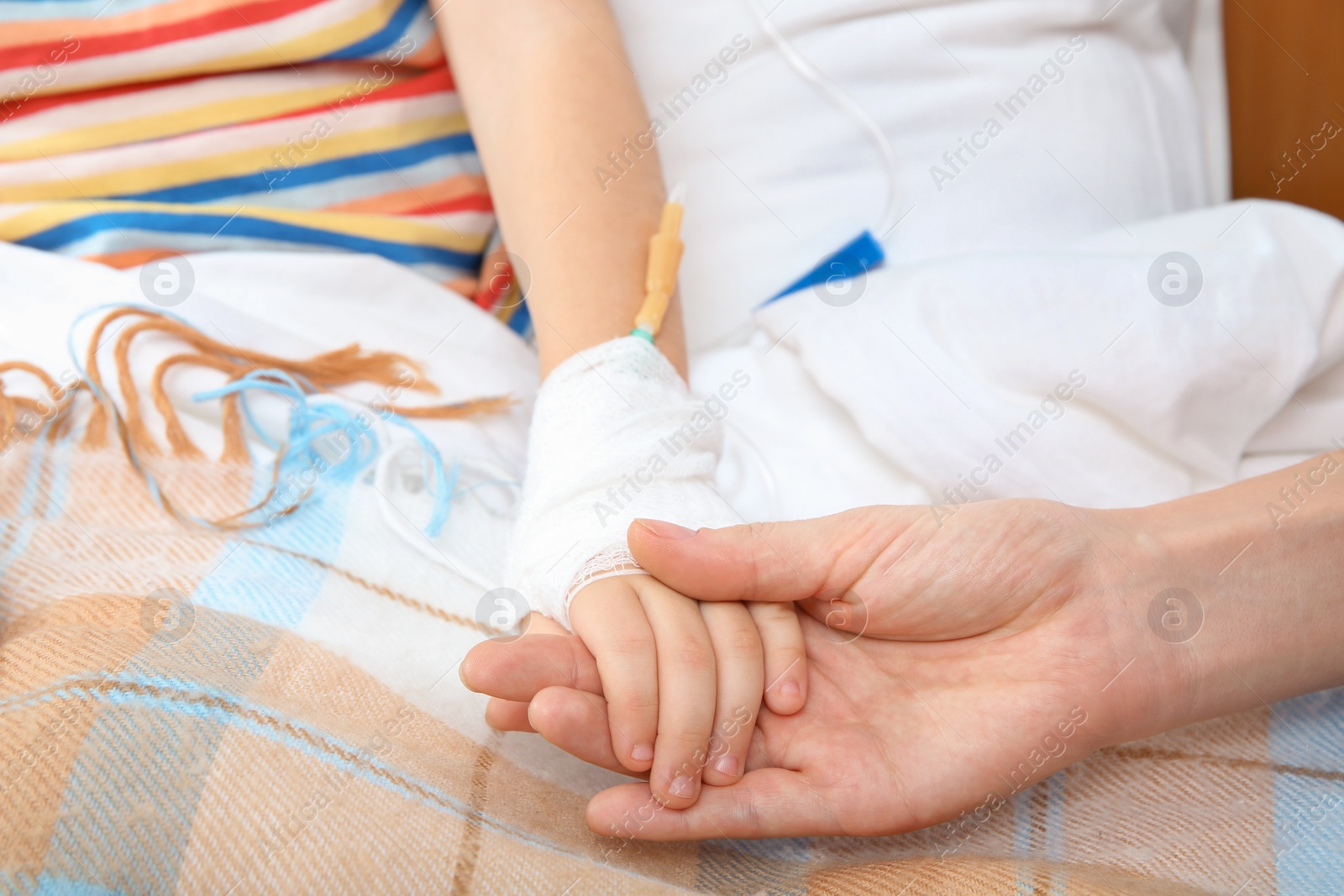 Photo of Doctor holding little child's hand with intravenous drip in hospital, closeup