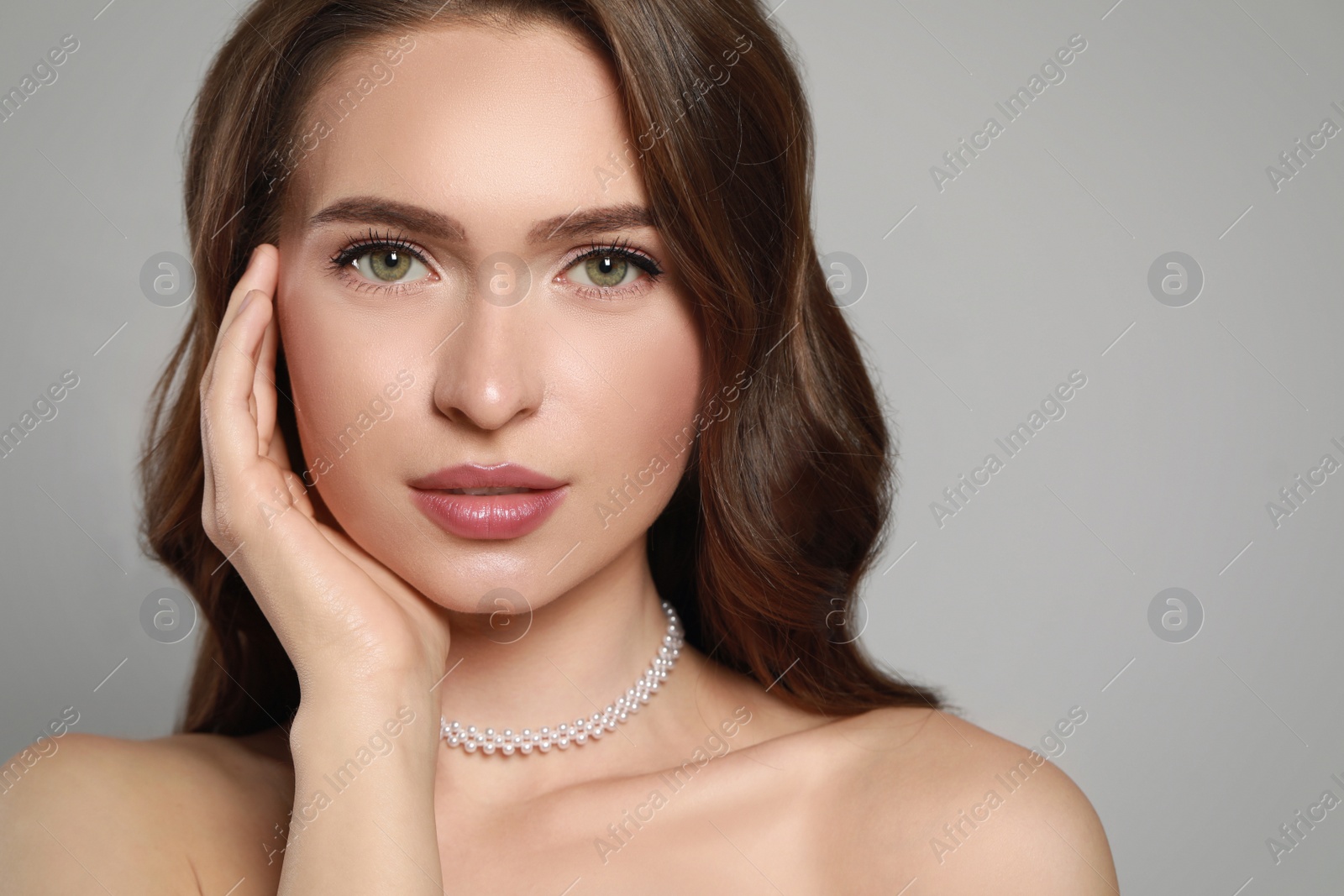 Photo of Young woman wearing elegant pearl necklace on grey background