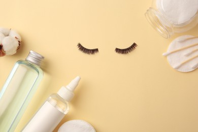 Photo of Flat lay composition with bottles of makeup removers and false eyelashes on yellow background