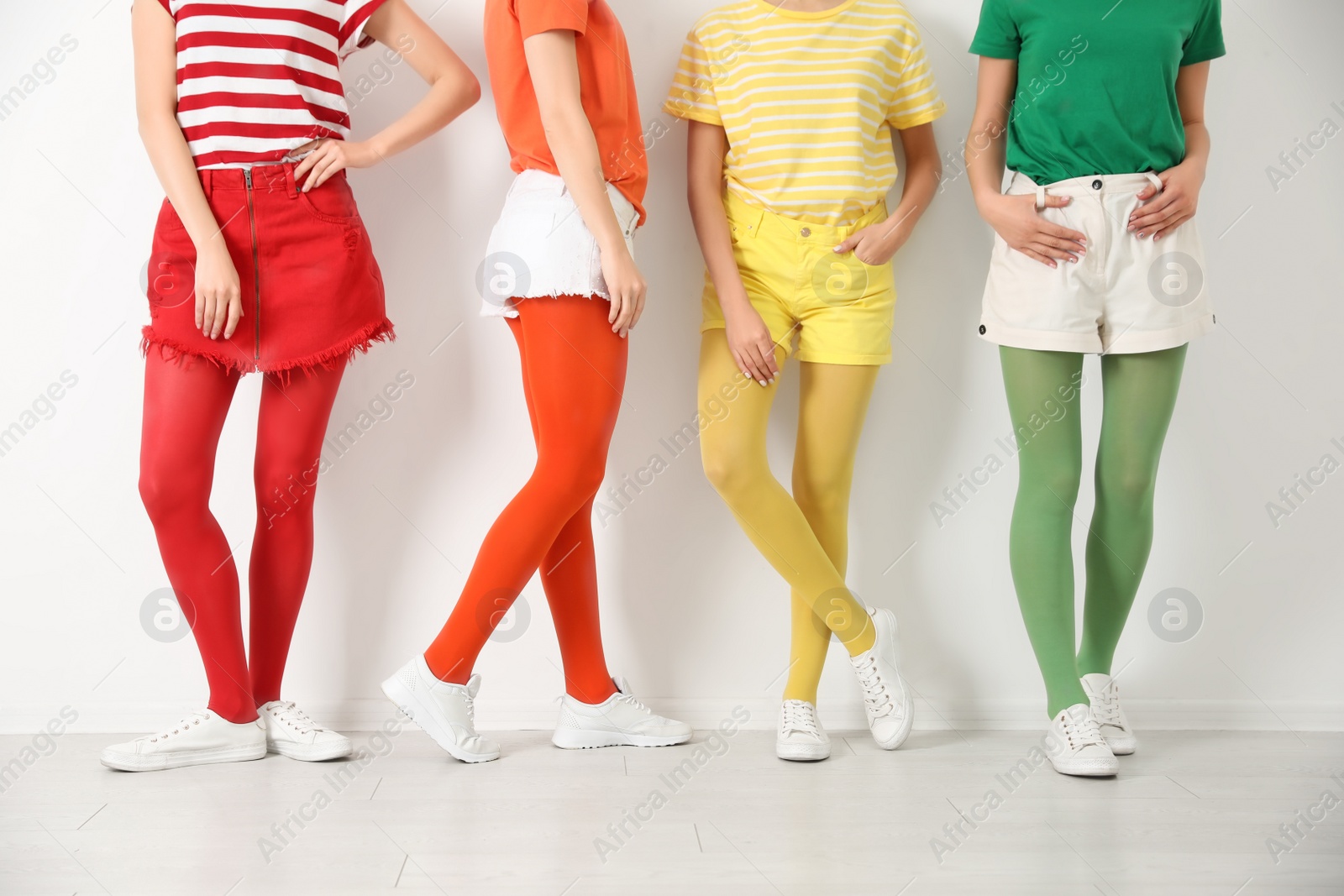 Photo of Women wearing bright tights near white wall, closeup