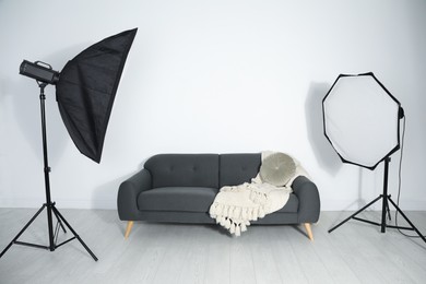 Comfortable sofa and professional lighting equipment in photo studio