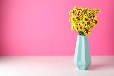 Vase with beautiful chrysanthemum flowers on white table. Space for text