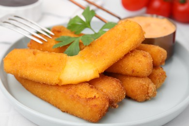 Tasty fried mozzarella sticks served with sauce and parsley on white table, closeup