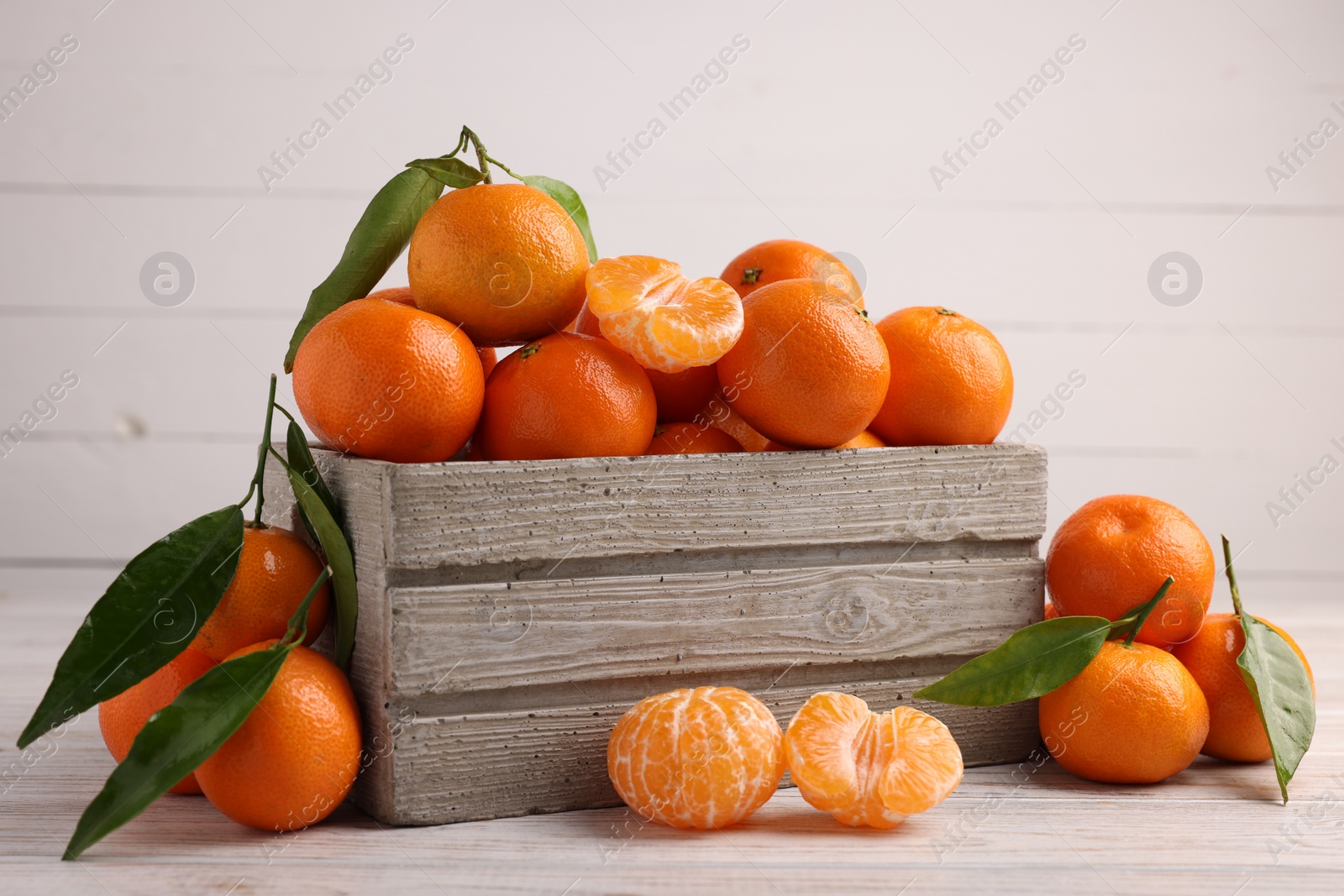 Photo of Delicious tangerines with leaves on light wooden table