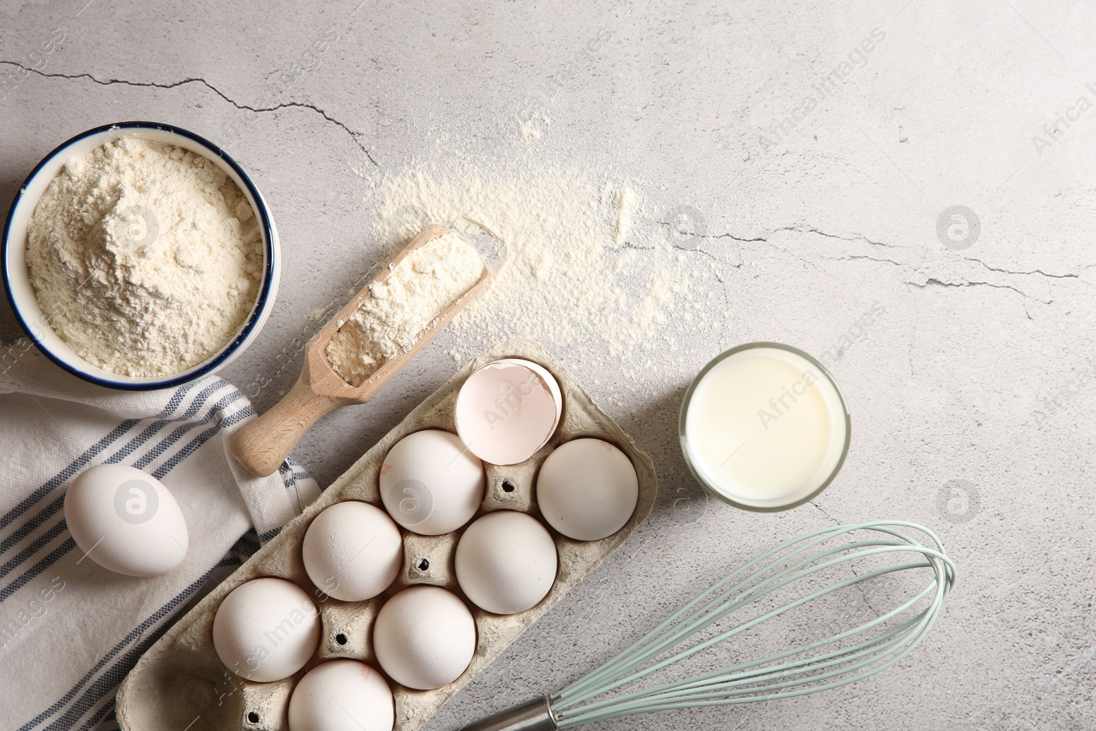 Photo of Making dough. Flour, eggs, milk and tools on light textured table, flat lay