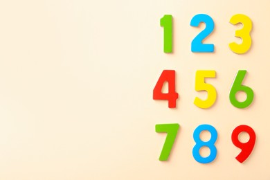 Colorful numbers on beige background, flat lay. Space for text