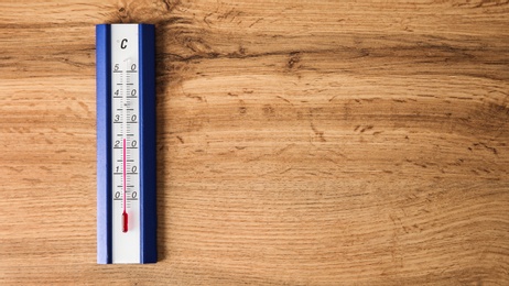 Photo of Weather thermometer on wooden table, top view. Space for text
