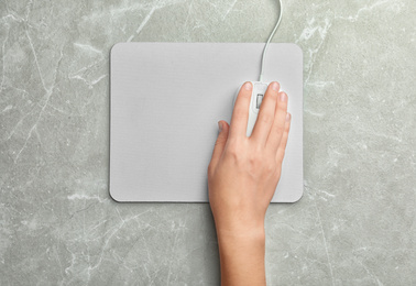 Photo of Woman using wired computer mouse on light grey marble table, top view. Space for text