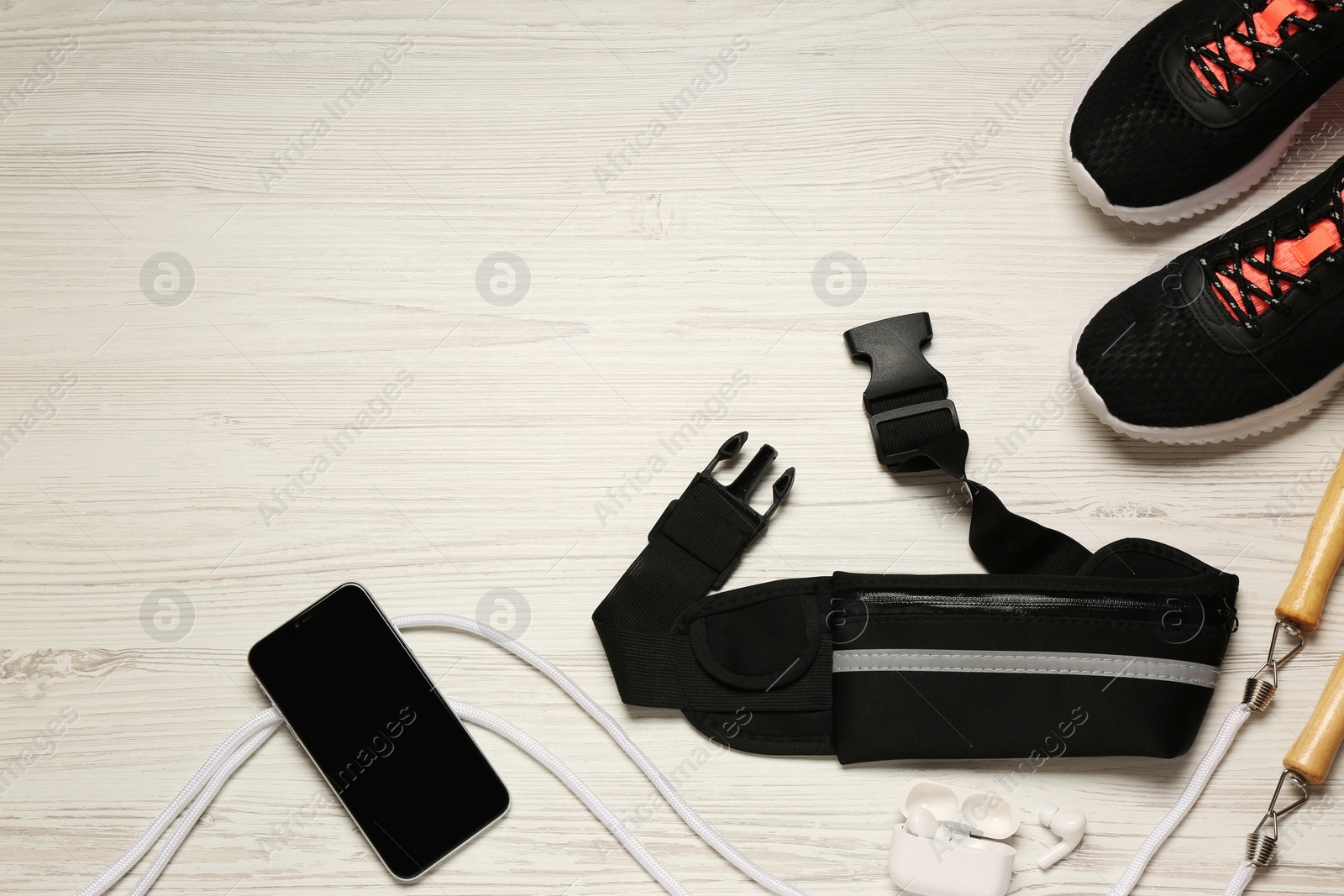 Photo of Flat lay composition with black waist bag on white wooden table, space for text
