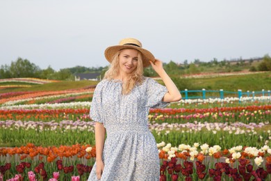 Happy woman in beautiful tulip field outdoors