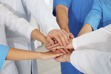 Photo of Team of medical workers holding hands together, closeup. Unity concept