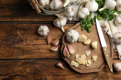 Photo of Flat lay composition with fresh sliced and whole garlic on wooden table, space for text. Organic product