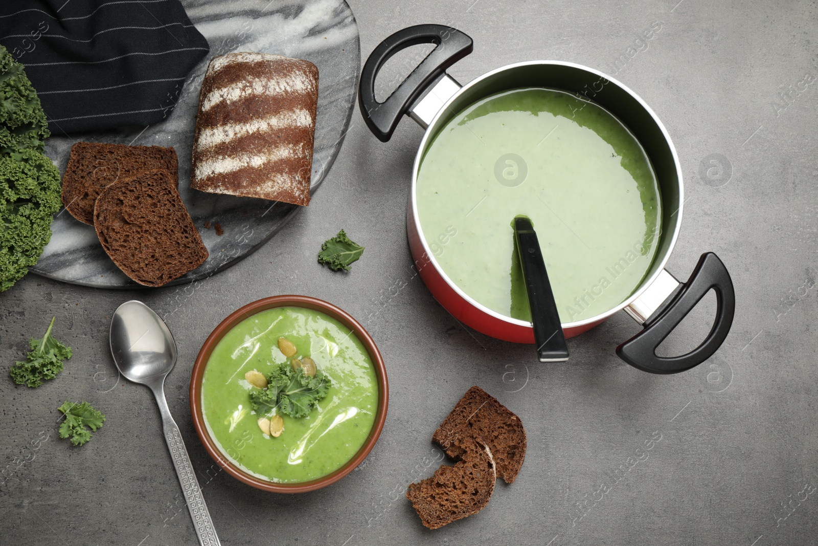 Photo of Tasty kale soup served on grey table, flat lay