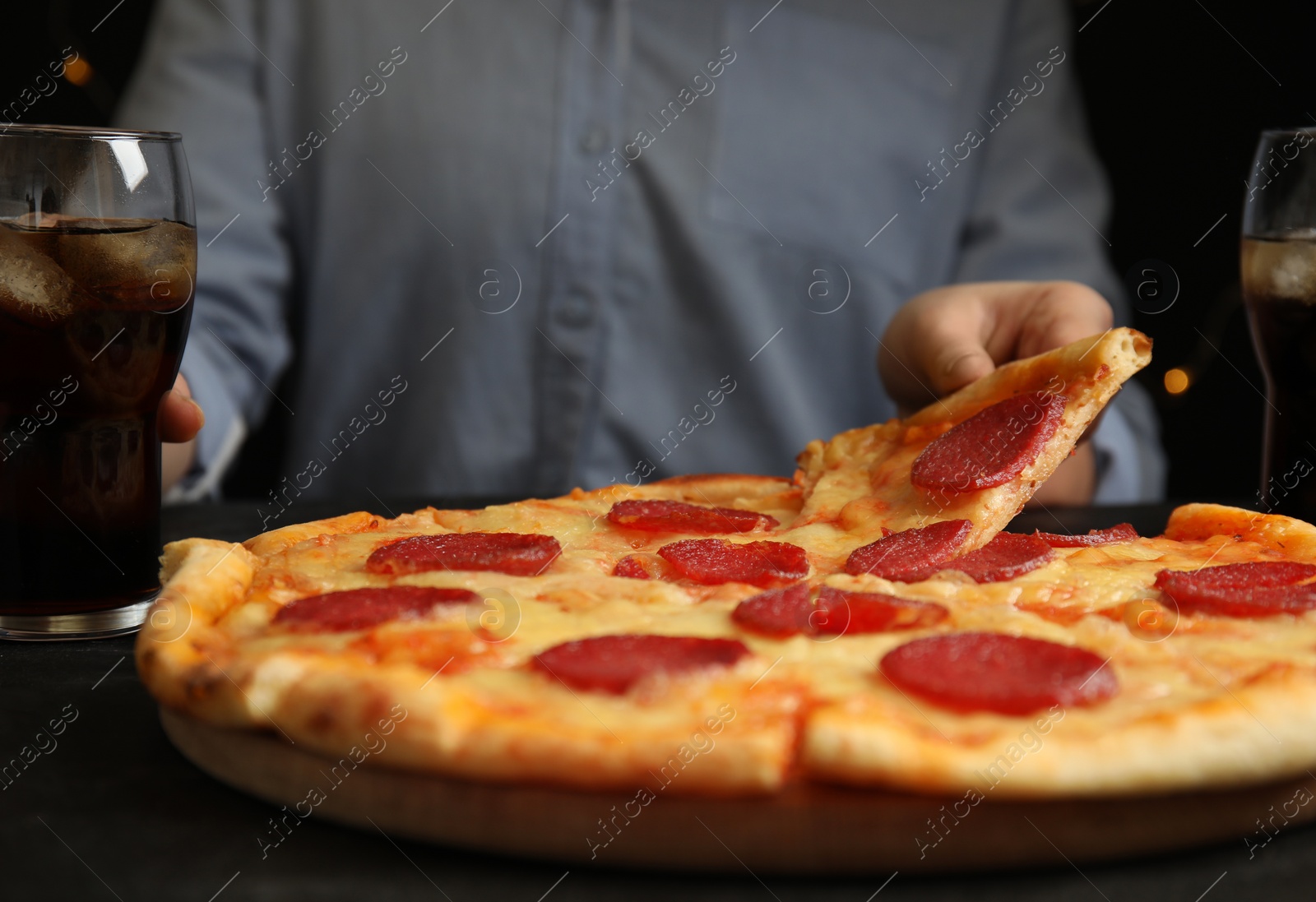 Photo of Woman taking tasty pepperoni pizza at table, closeup