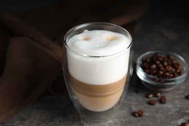 Photo of Delicious latte macchiato and coffee beans on grey table