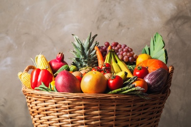Photo of Assortment of fresh organic fruits and vegetables in basket on grey background, closeup