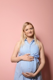 Photo of Beautiful pregnant woman in dress on color background