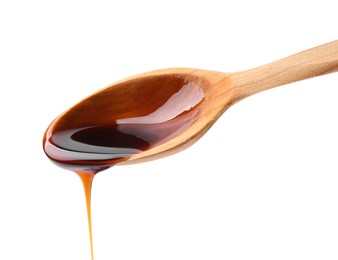 Photo of Pouring delicious caramel syrup from wooden spoon isolated on white