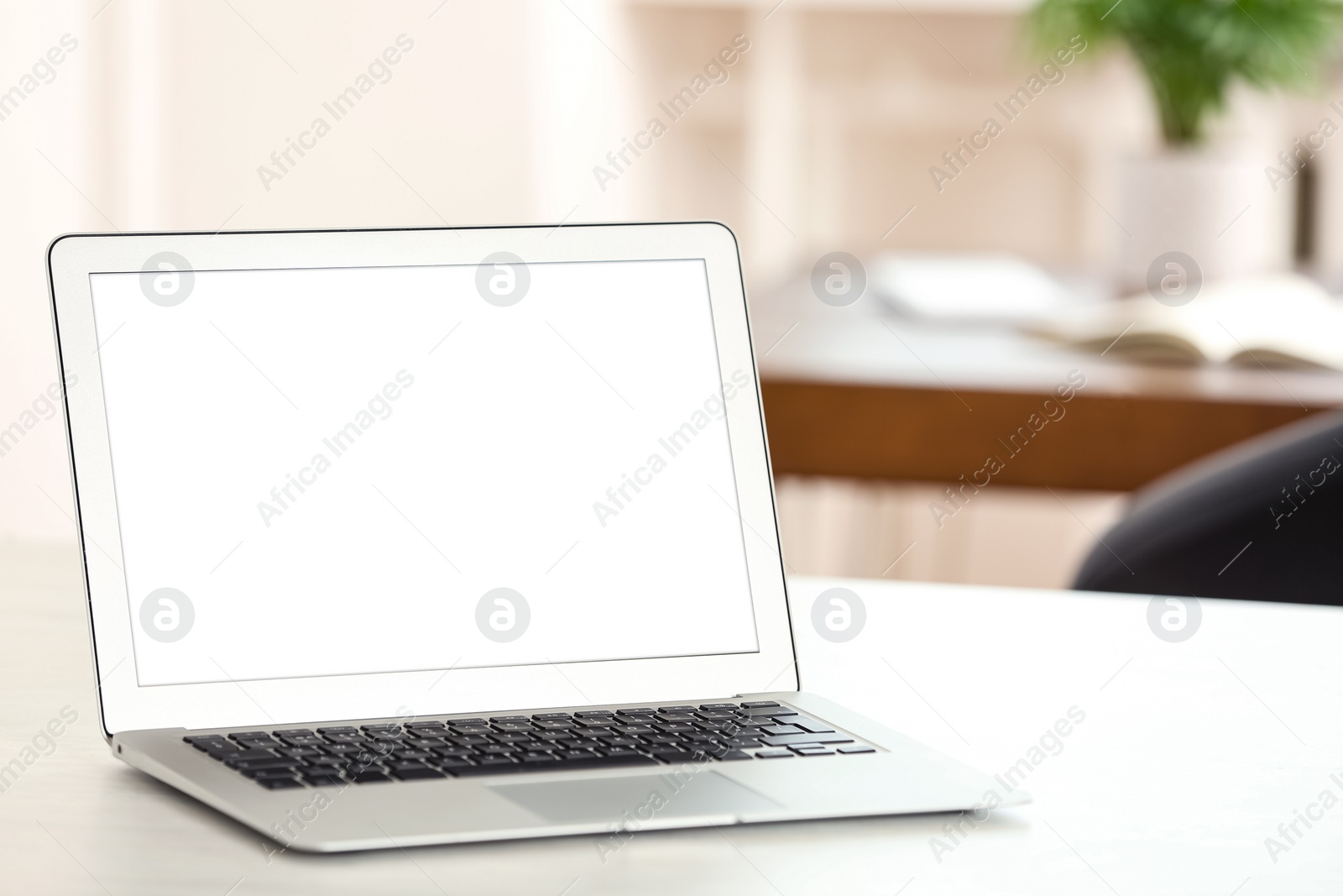 Photo of New modern laptop on white table in office. Space for text