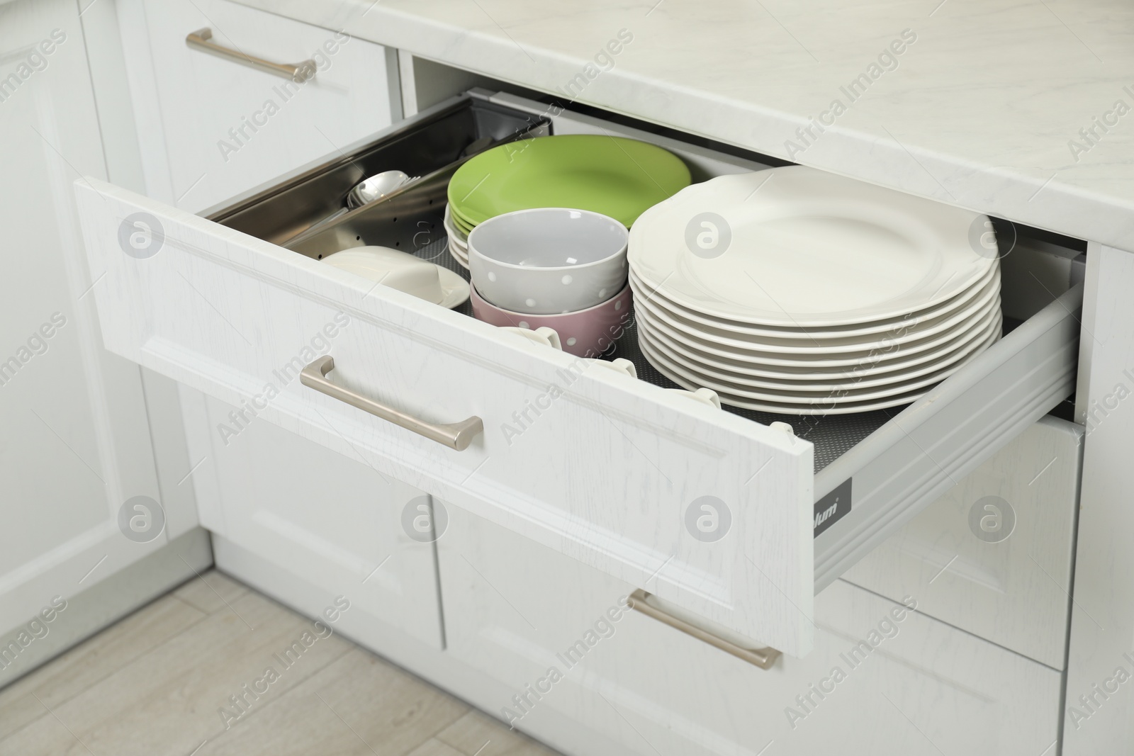 Photo of Clean plates and bowls in drawer indoors