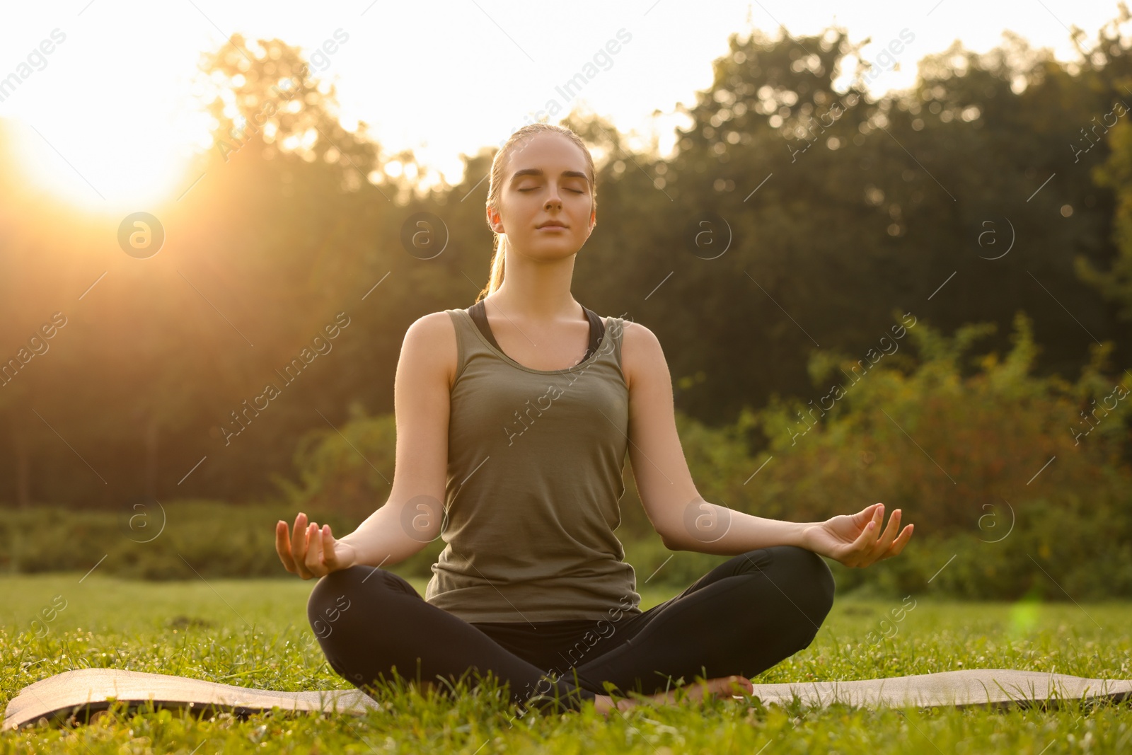 Photo of Beautiful woman practicing yoga outdoors on sunny day. Lotus pose