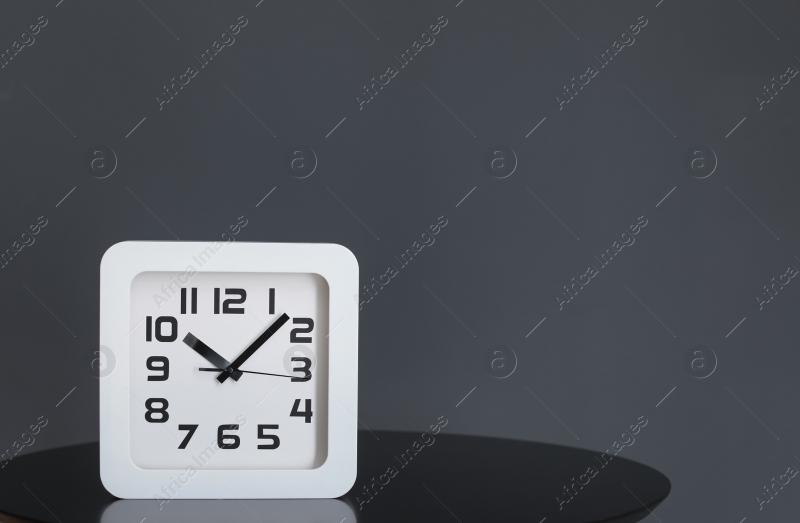 Photo of Modern clock on table. Time of day