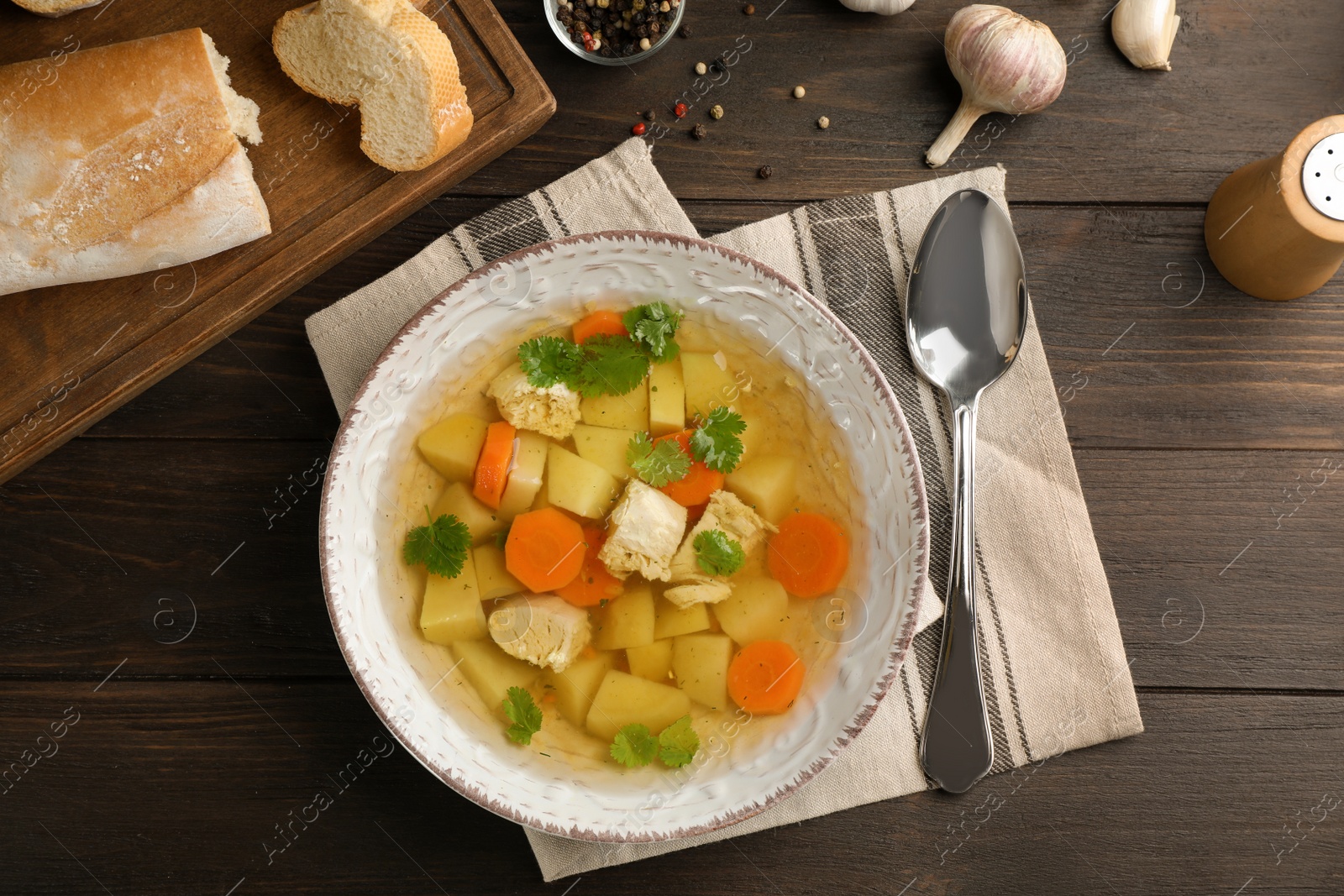 Photo of Dish with fresh homemade chicken soup served on wooden background, flat lay