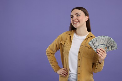 Happy woman with dollar banknotes on purple background, space for text