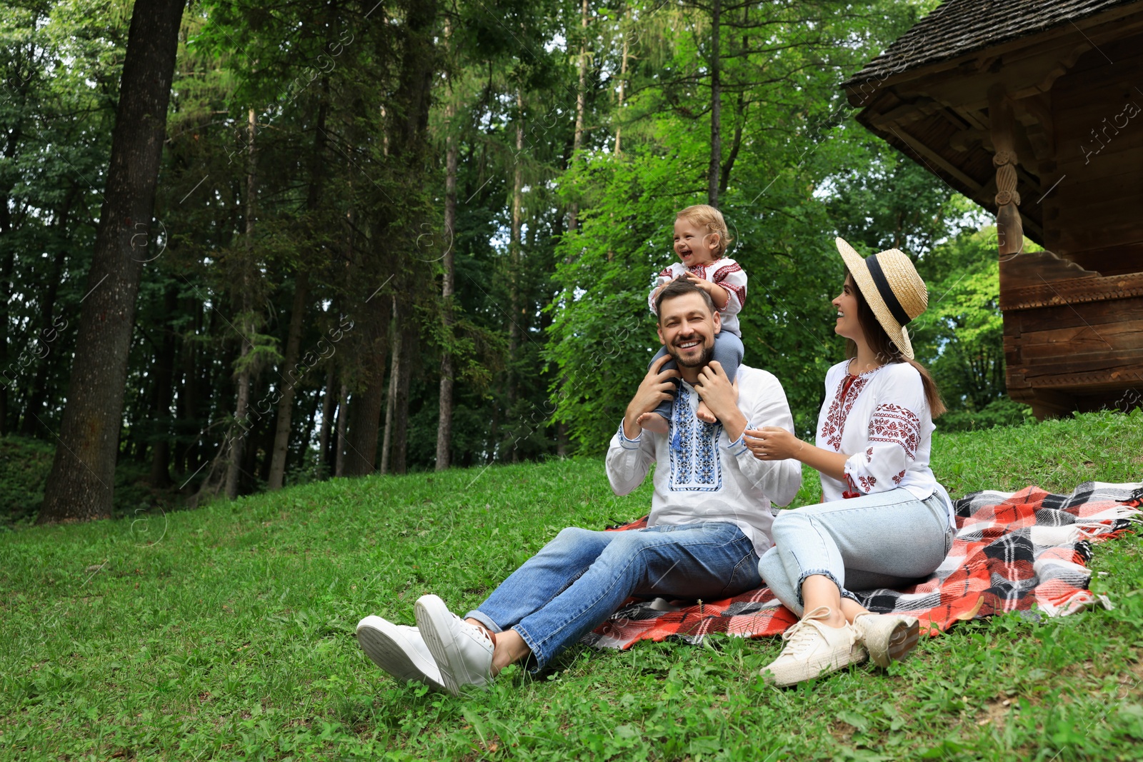 Photo of Happy family in Ukrainian national clothes on green grass outdoors