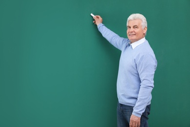 Photo of Portrait of senior teacher with chalk at green board, space for text