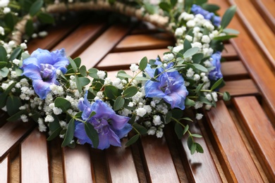 Photo of Beautiful flower wreath on wooden background, closeup