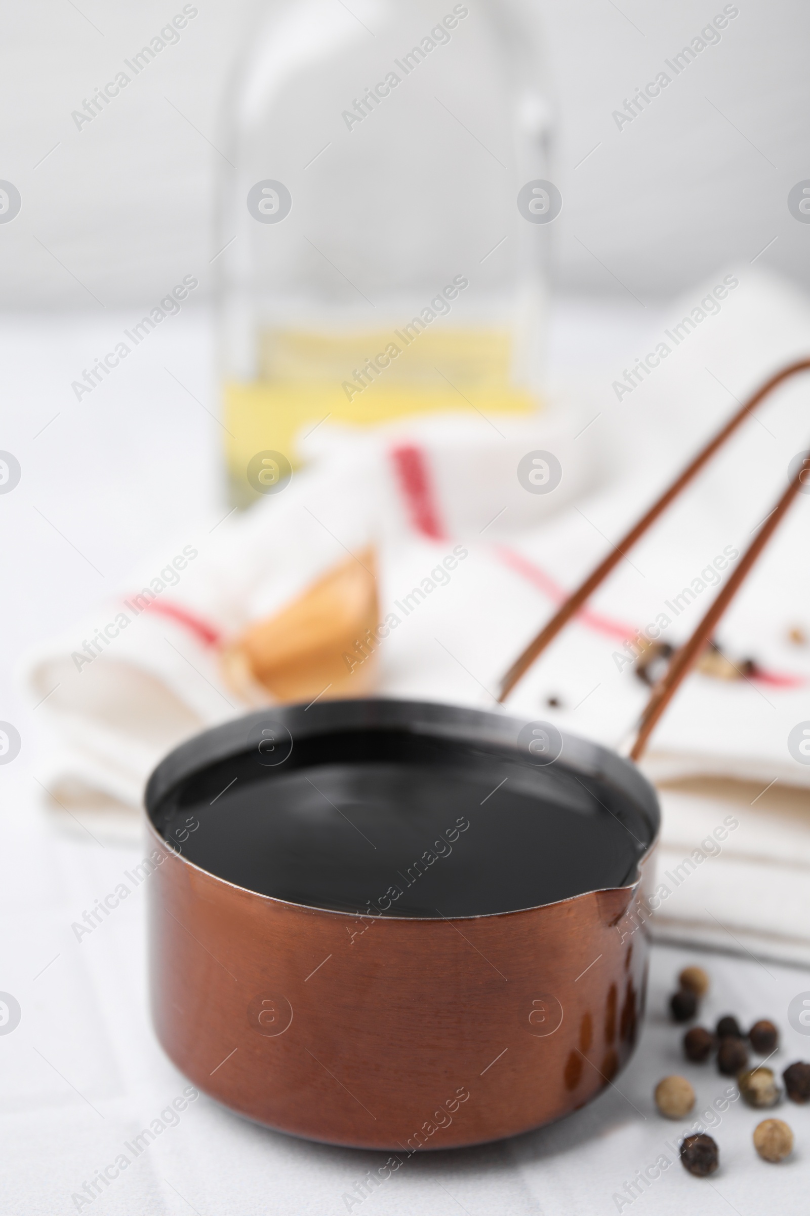 Photo of Metal small saucepan with balsamic vinegar and ingredients on white table