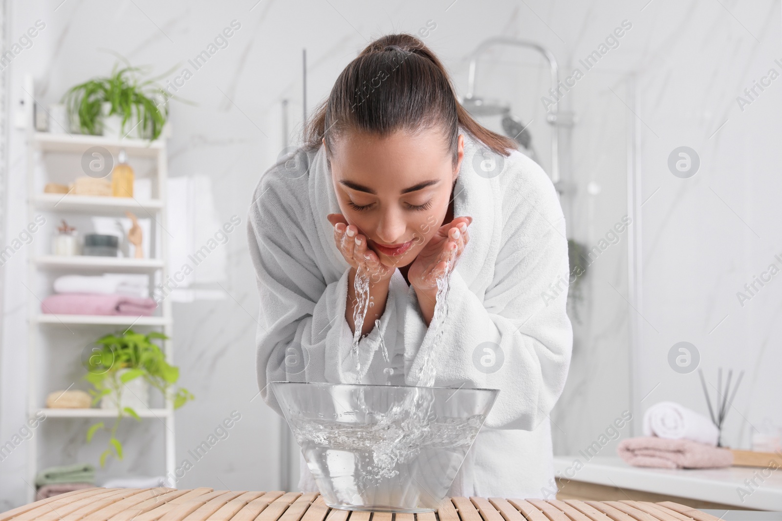 Photo of Beautiful young woman washing her face with water in bathroom