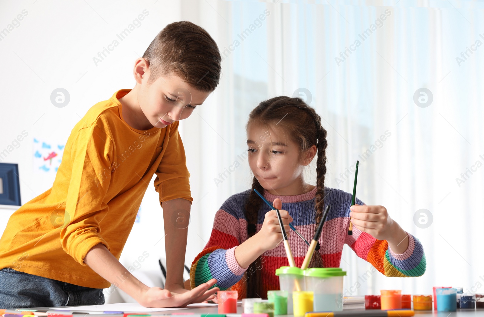 Photo of Little children painting picture at table indoors