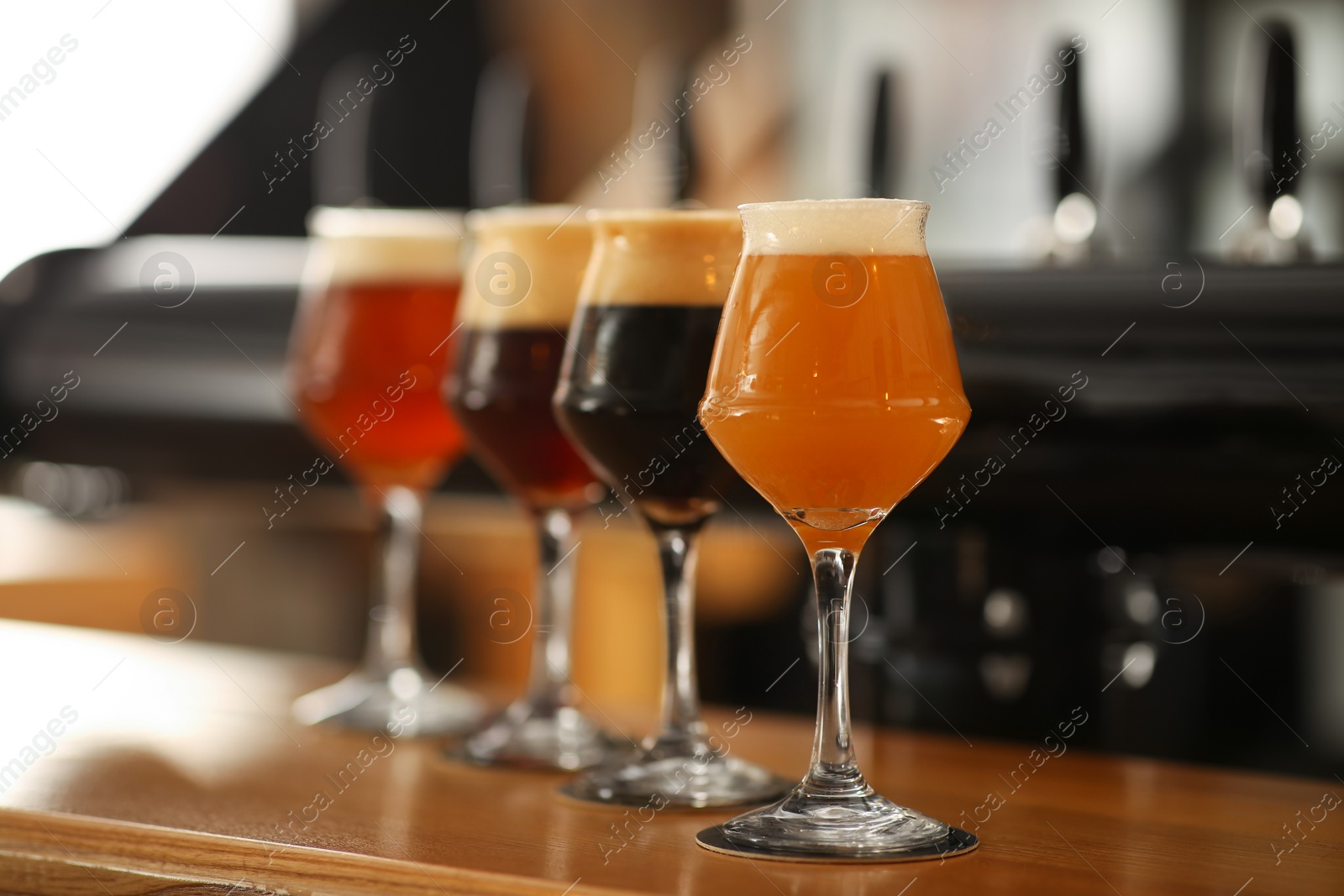 Photo of Different beers in glasses on bar counter